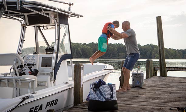 man lifting boy out of boat